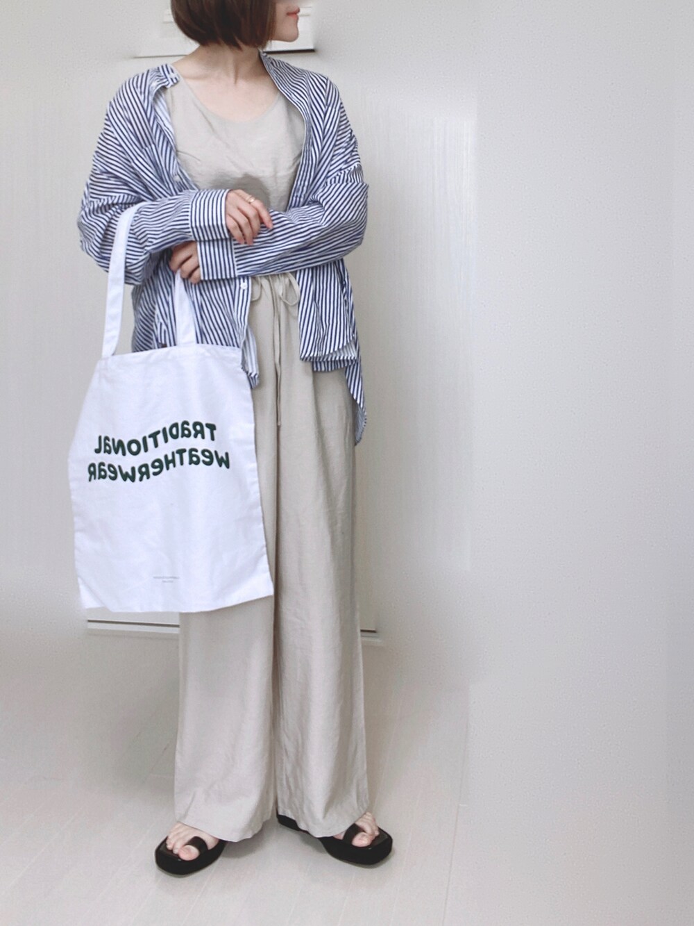 ブルー系のシャツ/ブラウス、ホワイト系のトートバッグ、ブラック系のサンダルを着用したレディースの夏コーディネートの2枚目の写真