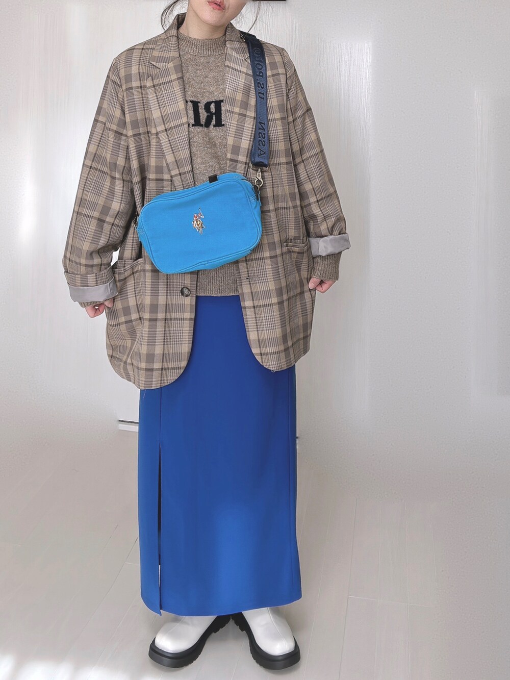 ブルー系のショルダーバッグ、ベージュ系のテーラードジャケット、ベージュ系のニット/セーターを着用したレディースの冬コーディネートの5枚目の写真