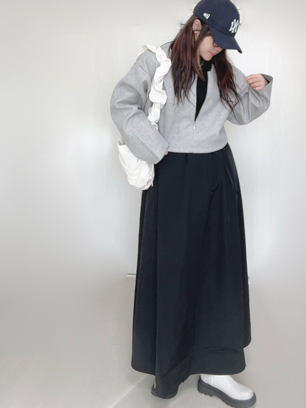 グレー系のワンピース、ホワイト系のショルダーバッグ、ホワイト系のブーツを着用したレディースの秋コーディネートの5枚目の写真