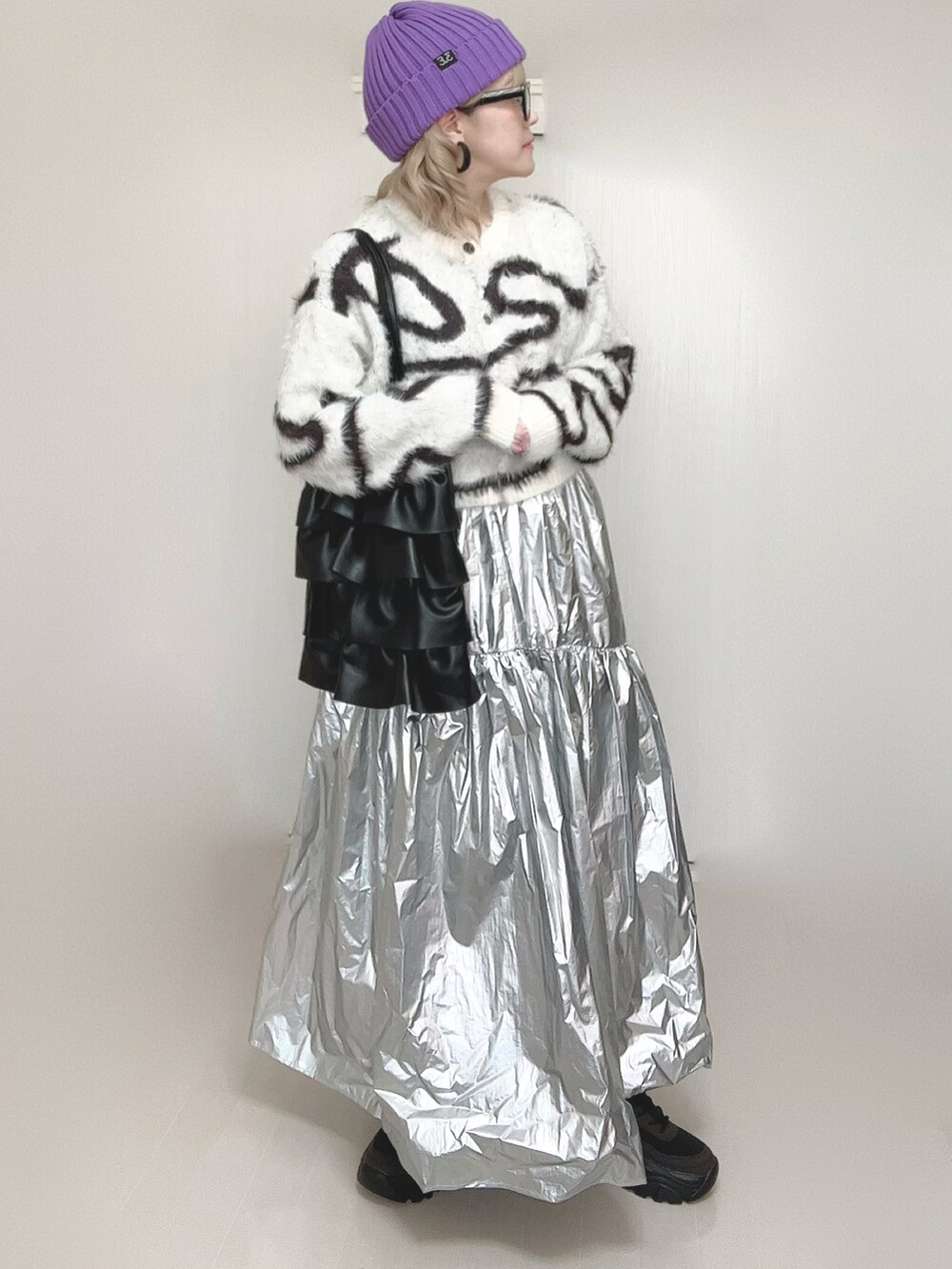 ホワイト系のカーディガン/ボレロ、シルバー系のスカート、ブラック系のスニーカーを着用したレディースの春コーディネートの5枚目の写真