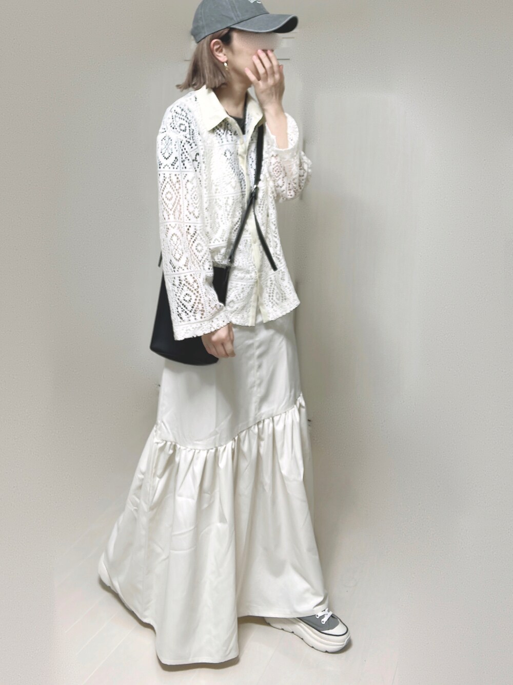 ホワイト系のジャンパースカート、ブラック系のショルダーバッグ、グレー系のスニーカーを着用したレディースの春コーディネートの5枚目の写真