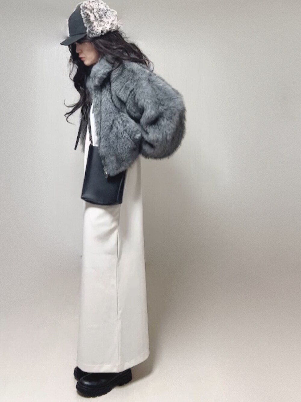 グレー系のブルゾン、ブラック系のブーツ、ホワイト系のワンピースを着用したレディースの秋コーディネートの3枚目の写真