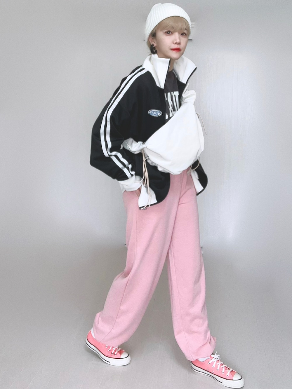 ホワイト系のショルダーバッグ、ブラック系のブルゾン、ピンク系のスウェットパンツを着用したレディースの冬コーディネートの2枚目の写真