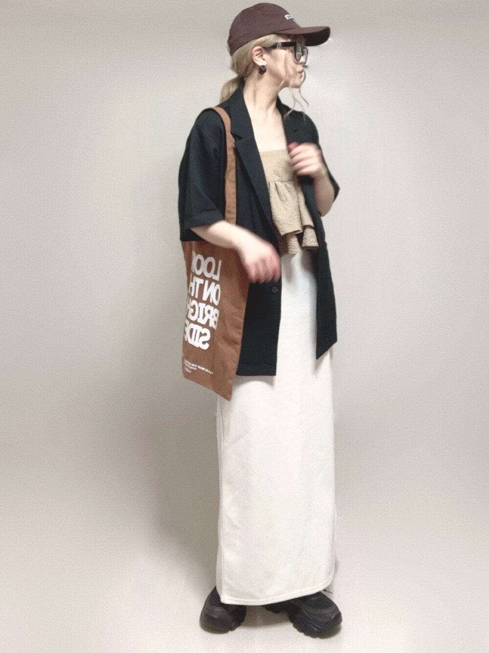 ブラック系のテーラードジャケット、ベージュ系のキャミソール、ブラック系のスニーカーを着用したレディースの夏コーディネートの4枚目の写真