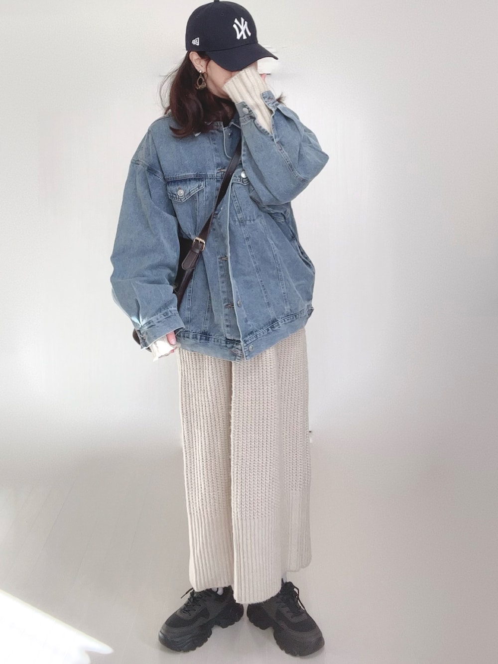 ブルー系のデニムジャケット、ホワイト系のワンピース、ブラック系のスニーカーを着用したレディースの冬コーディネートの2枚目の写真