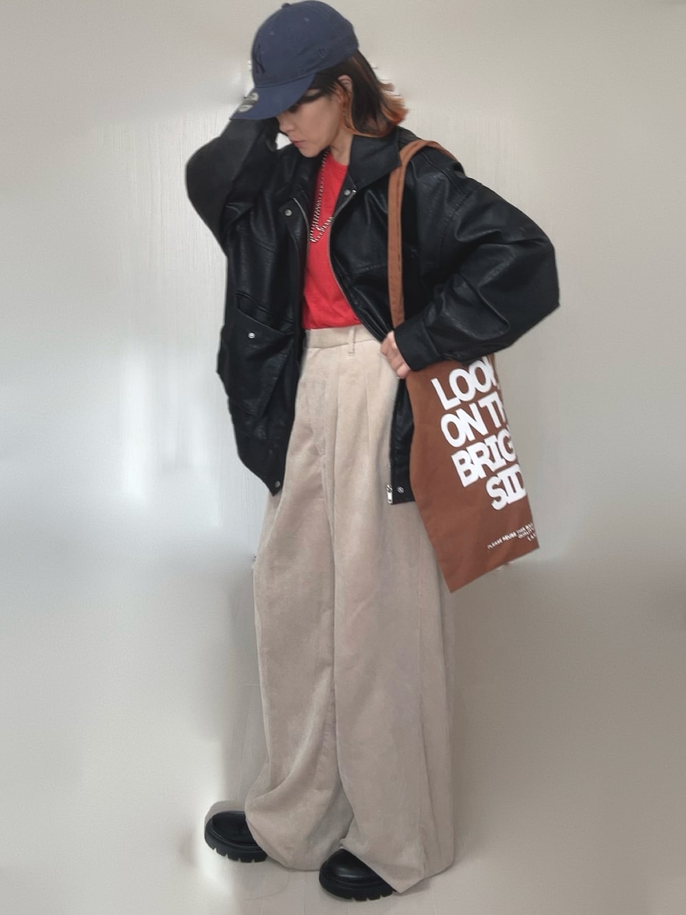 ブラック系のブルゾン、レッド系のTシャツ/カットソー、ブラック系のブーツを着用したレディースの冬コーディネートの3枚目の写真