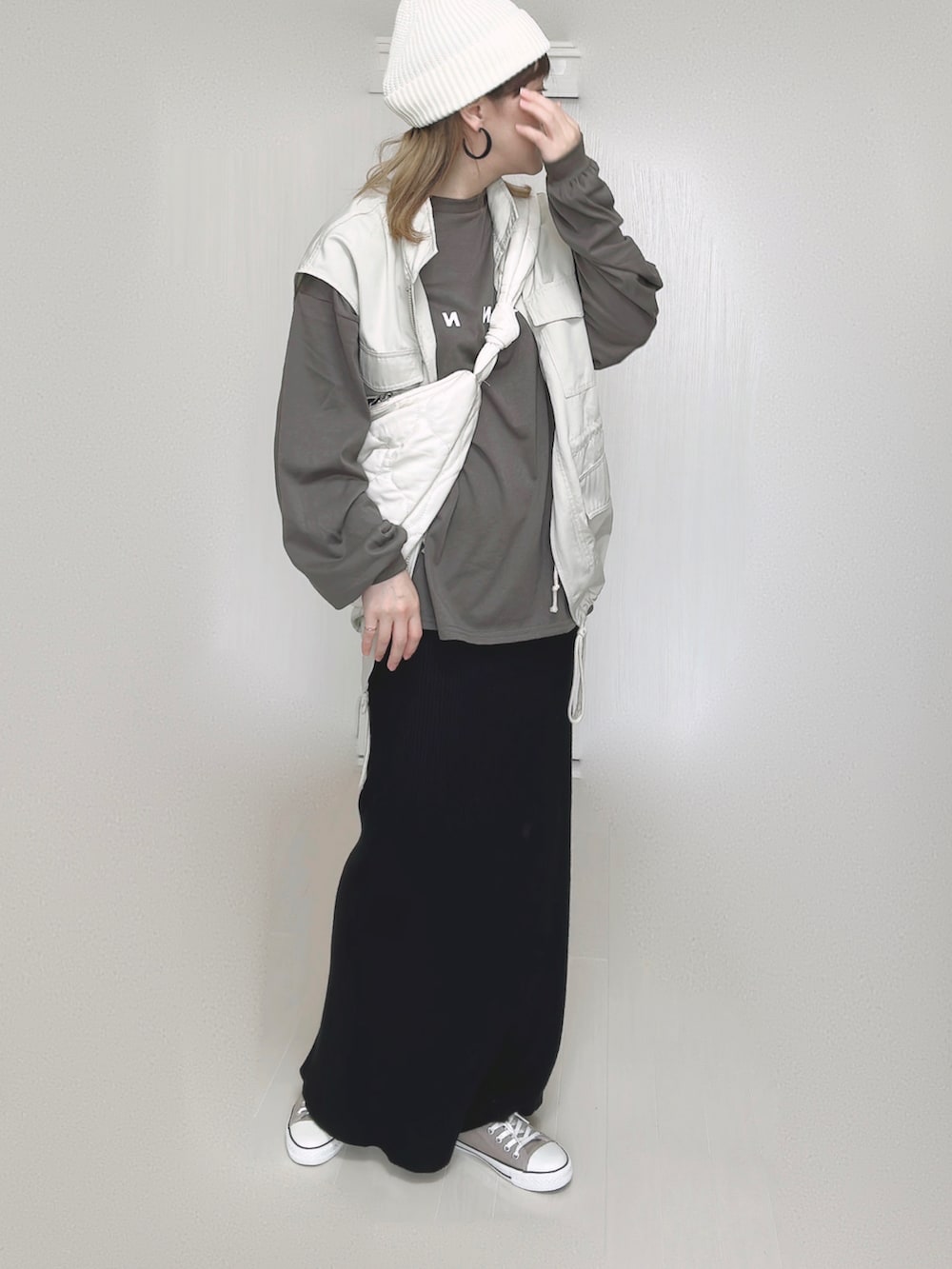 ホワイト系のショルダーバッグ、ホワイト系のベスト、ブラック系のスカートを着用したレディースの秋コーディネートの3枚目の写真