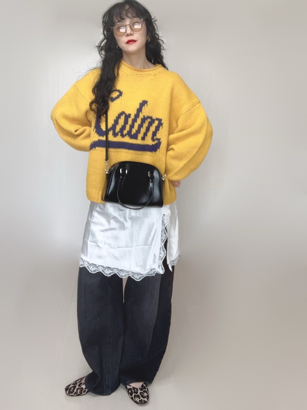 イエロー系のニット/セーター、ブラック系のデニムパンツ、ホワイト系のワンピースを着用したレディースの春コーディネートの5枚目の写真