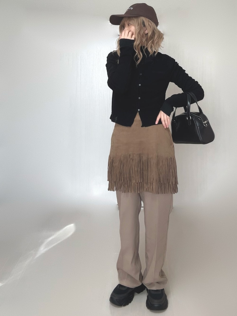 ブラック系のカーディガン/ボレロ、ブラック系のTシャツ/カットソー、ベージュ系のスカートを着用したレディースの冬コーディネートの2枚目の写真