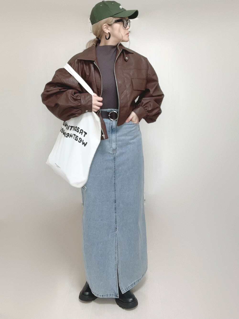 ブラウン系のブルゾン、ホワイト系のトートバッグ、ブラック系のブーツを着用したレディースの秋コーディネートの5枚目の写真