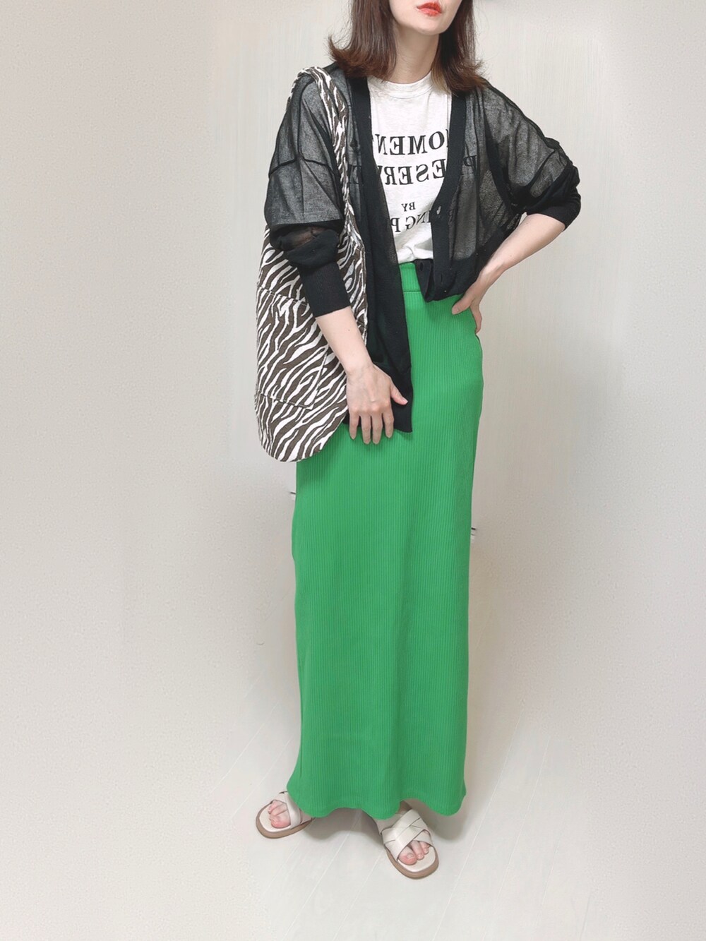 ブラック系のカーディガン/ボレロ、グリーン系のスカート、ホワイト系のサンダルを着用したレディースの夏コーディネートの4枚目の写真