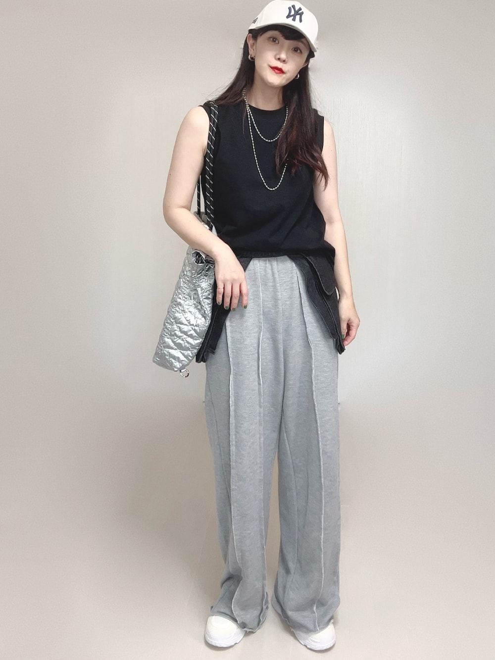 グレー系のスウェットパンツ、シルバー系のトートバッグ、ホワイト系のスニーカーを着用したレディースの夏コーディネートの4枚目の写真