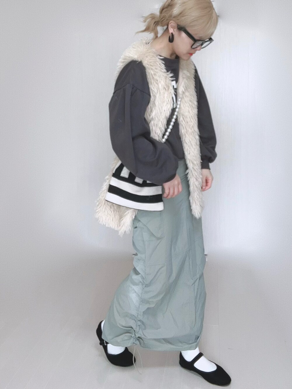 グリーン系のスカート、ホワイト系のベスト、ホワイト系のショルダーバッグを着用したレディースの冬コーディネートの5枚目の写真