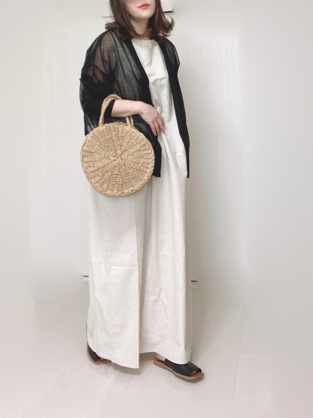 ブラック系のカーディガン/ボレロ、ホワイト系のワンピース、ブラック系のサンダルを着用したレディースの春コーディネートの4枚目の写真