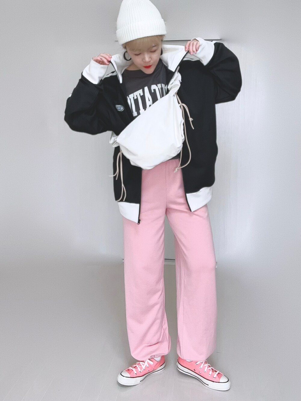 ホワイト系のショルダーバッグ、ブラック系のブルゾン、ピンク系のスウェットパンツを着用したレディースの冬コーディネートの4枚目の写真