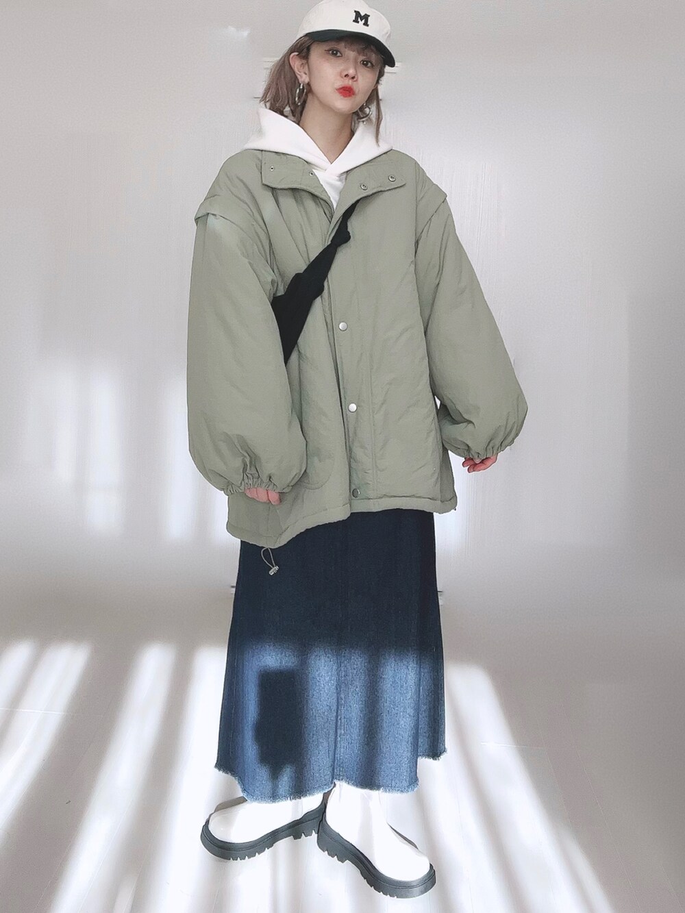 グリーン系のダウンジャケット/コート、ホワイト系のパーカー、ブルー系のセットアップを着用したレディースの冬コーディネートの4枚目の写真