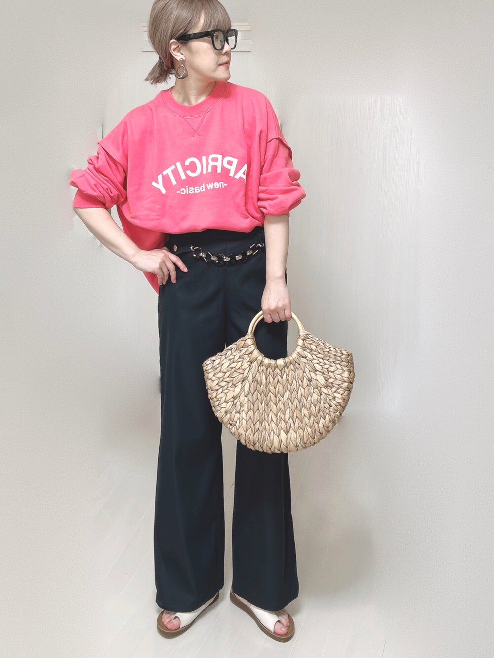 ピンク系のスウェット、ブルー系のスラックス、ベージュ系のかごバッグを着用したレディースの春コーディネートの4枚目の写真