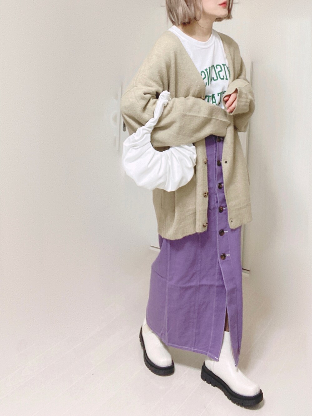 ベージュ系のカーディガン/ボレロ、ホワイト系のTシャツ/カットソー、パープル系のスカートを着用したレディースの冬コーディネートの5枚目の写真