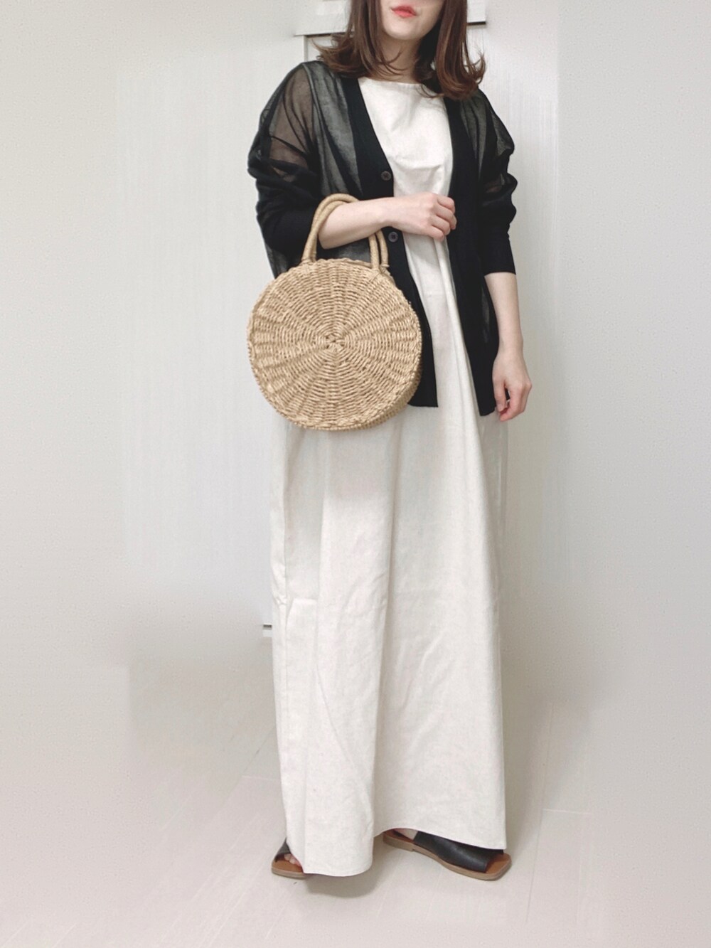 ブラック系のカーディガン/ボレロ、ホワイト系のワンピース、ブラック系のサンダルを着用したレディースの春コーディネートの3枚目の写真