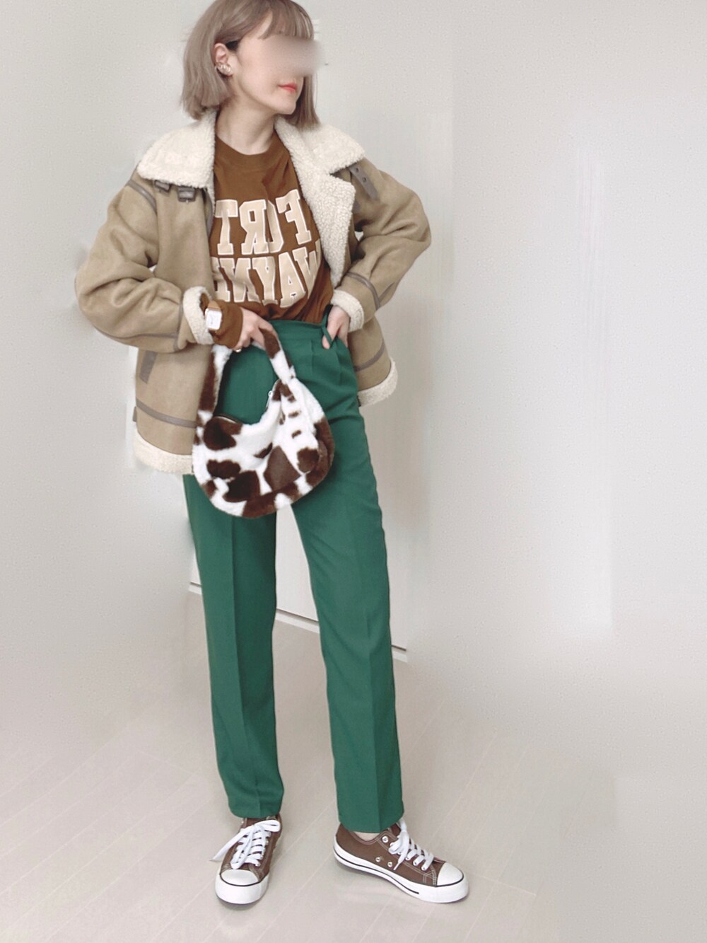 ベージュ系のムートンコート、ブラウン系のTシャツ/カットソー、グリーン系のスラックスを着用したレディースの冬コーディネートの2枚目の写真