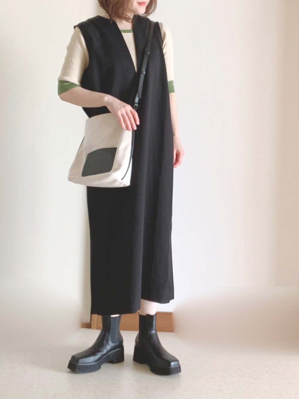 ホワイト系のショルダーバッグ、ブラック系のワンピース、ブラック系のブーツを着用したレディースの秋コーディネートの3枚目の写真