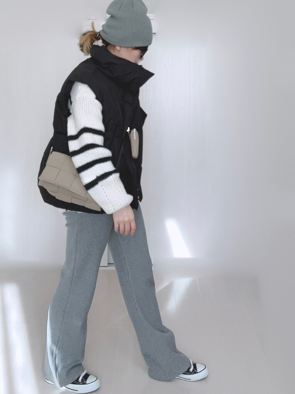 ブラック系のダウンベスト、ホワイト系のニット/セーター、グレー系のその他パンツを着用したレディースの冬コーディネートの2枚目の写真