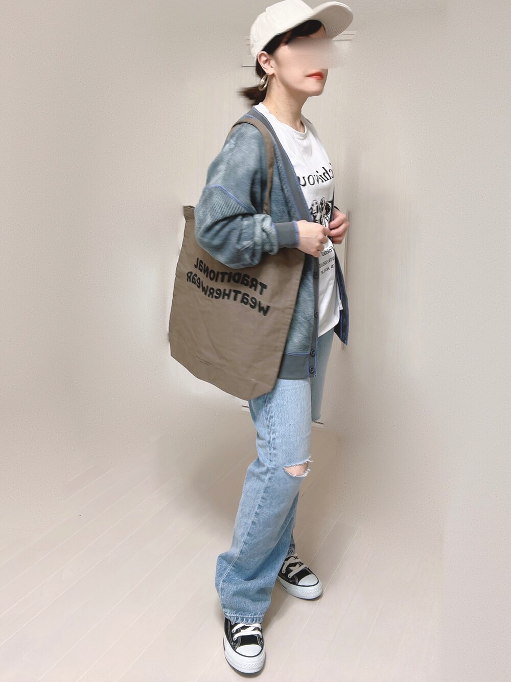 ブルー系のデニムパンツ、ブラック系のカーディガン/ボレロ、ブラウン系のトートバッグを着用したレディースの春コーディネートの5枚目の写真