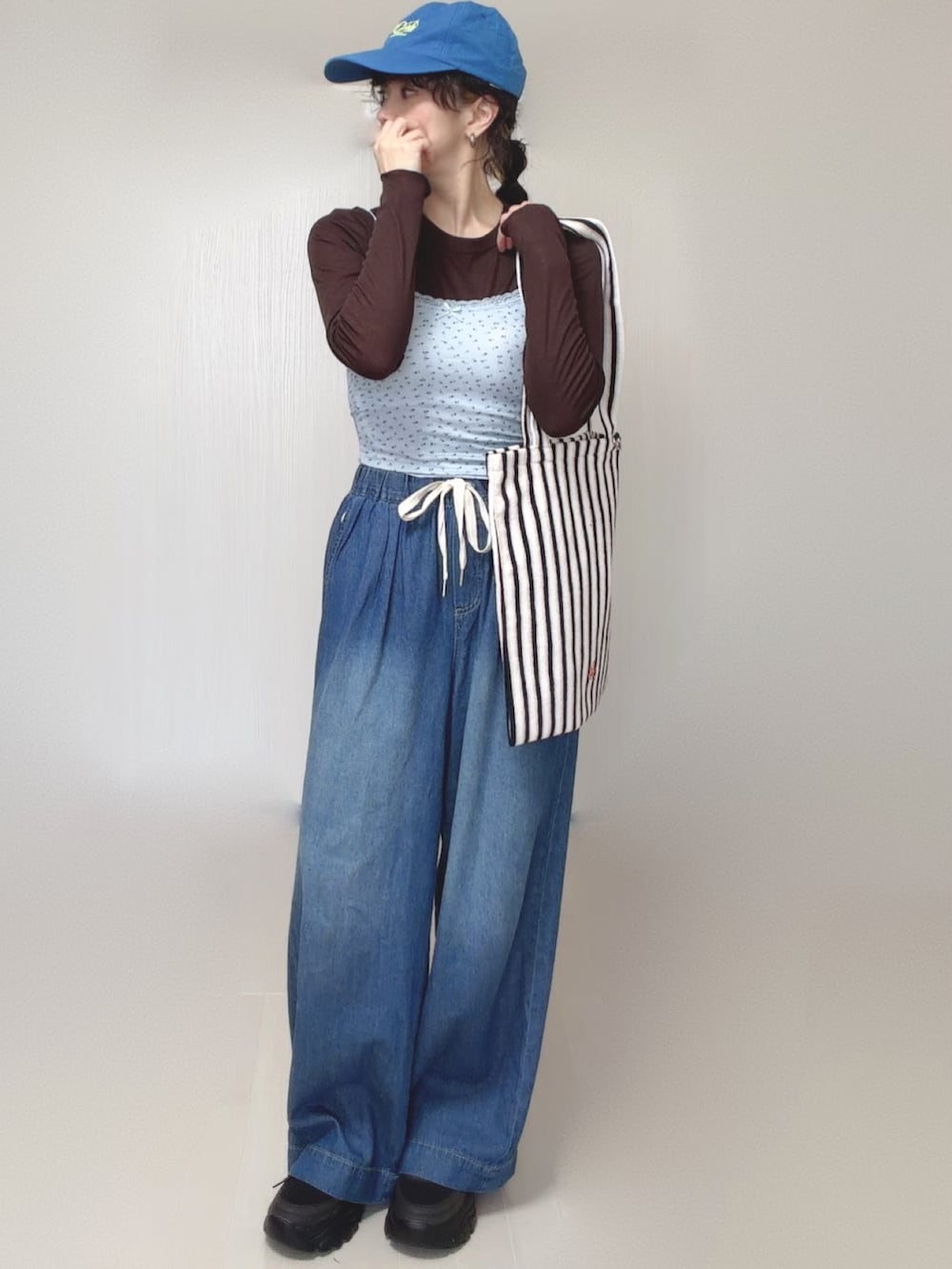 ブルー系のキャミソール、ブルー系のデニムパンツ、ホワイト系のトートバッグを着用したレディースの春コーディネートの3枚目の写真