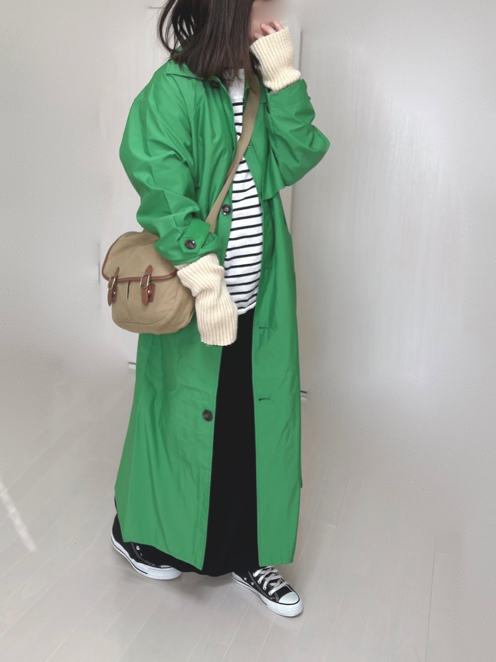 グリーン系のトレンチコート、ブラック系のTシャツ/カットソー、ベージュ系のショルダーバッグを着用したレディースの冬コーディネートの4枚目の写真