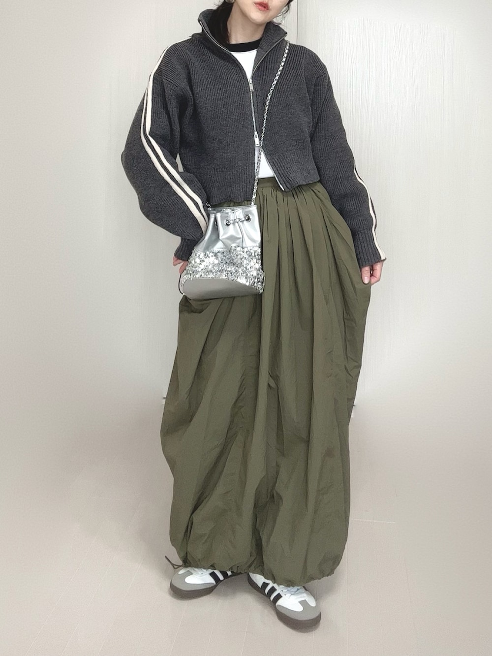 グレー系のニット/セーター、シルバー系のショルダーバッグ、グリーン系のスカートを着用したレディースの冬コーディネートの2枚目の写真