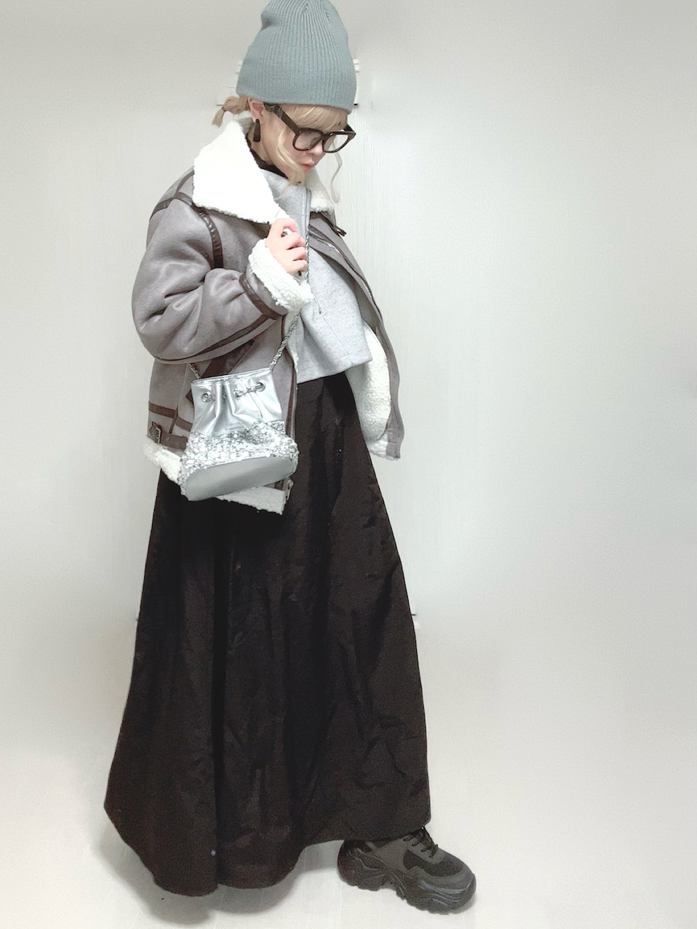 グレー系のムートンコート、グレー系のワンピース、シルバー系のショルダーバッグを着用したレディースの冬コーディネートの4枚目の写真