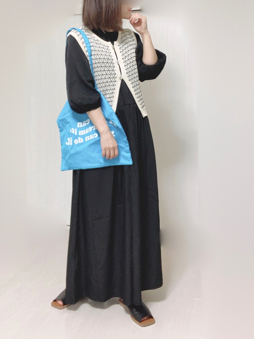 ブラック系のワンピース、ブルー系のトートバッグ、ブラック系のサンダルを着用したレディースの夏コーディネートの2枚目の写真