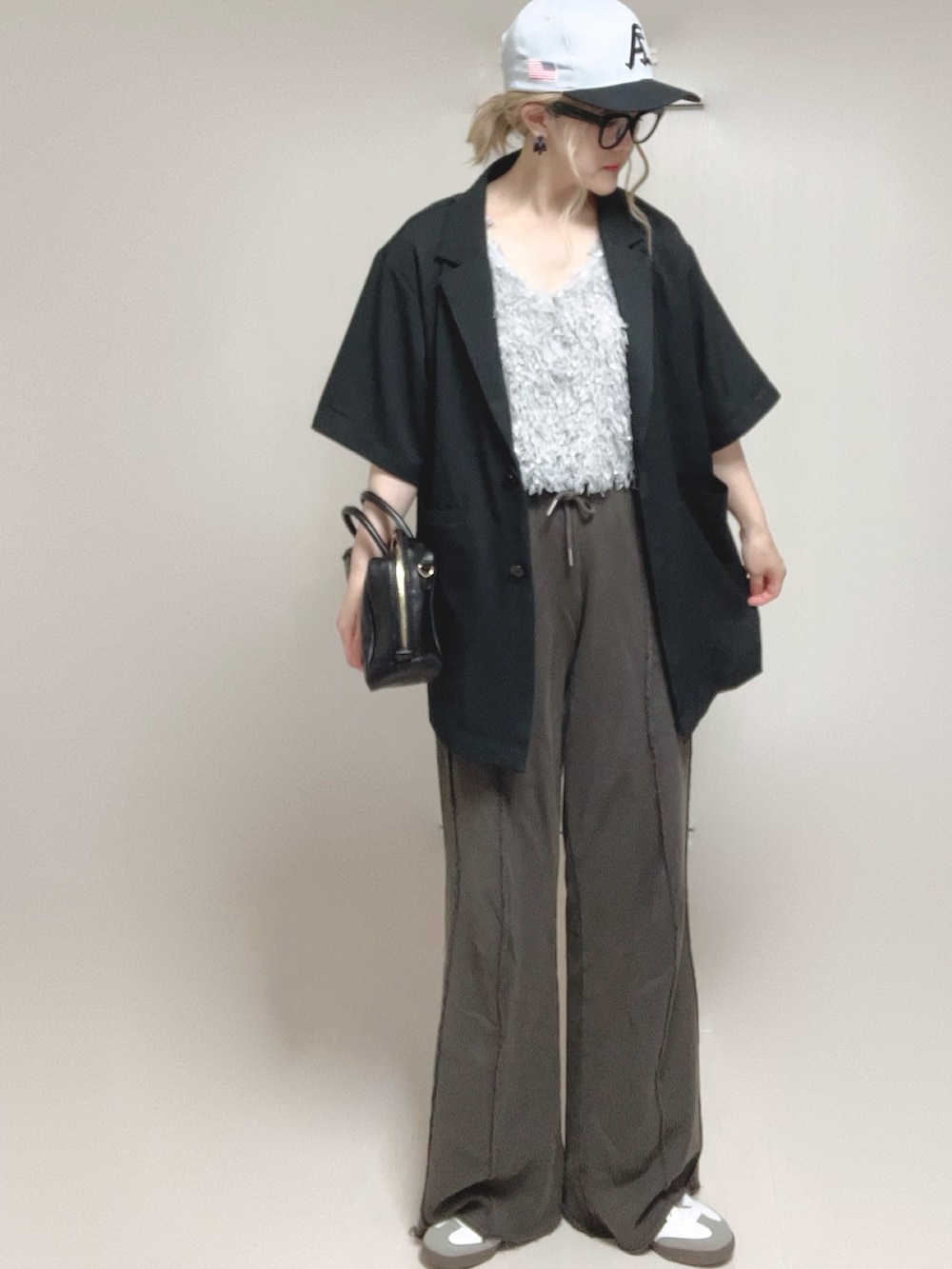 グレー系のベスト、ブラック系のテーラードジャケット、ブラック系のスウェットパンツを着用したレディースの夏コーディネートの4枚目の写真