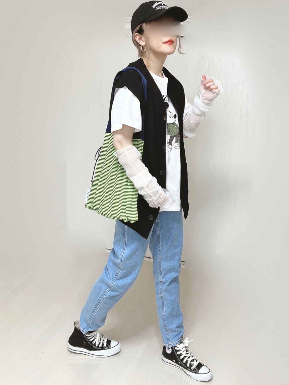 ブルー系のデニムパンツ、ブラック系のベスト、ホワイト系のTシャツ/カットソーを着用したレディースの春コーディネートの4枚目の写真