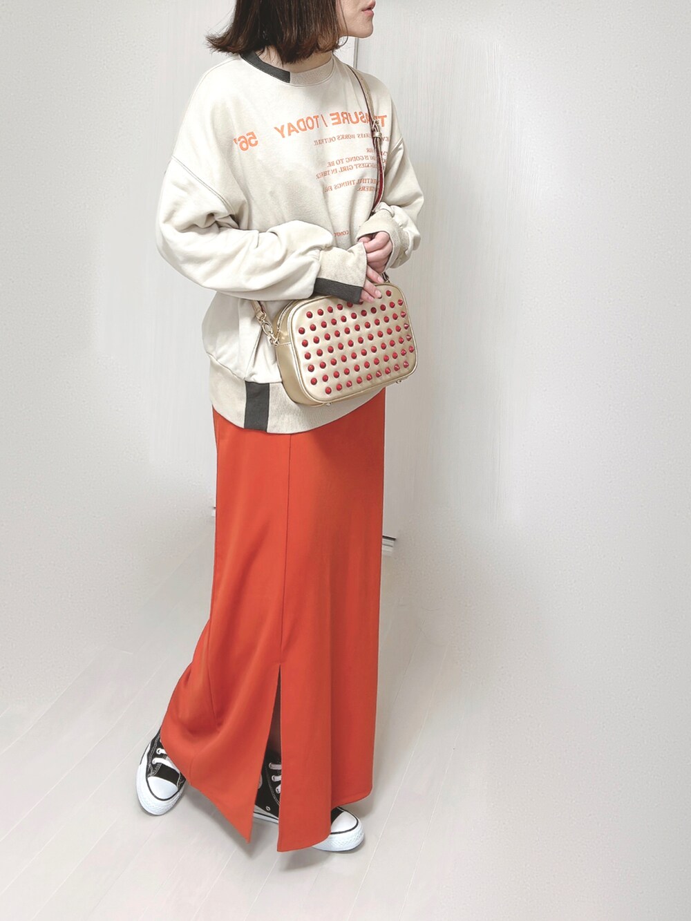 ベージュ系のスウェット、ゴールド系のショルダーバッグ、オレンジ系のスカートを着用したレディースの春コーディネートの5枚目の写真