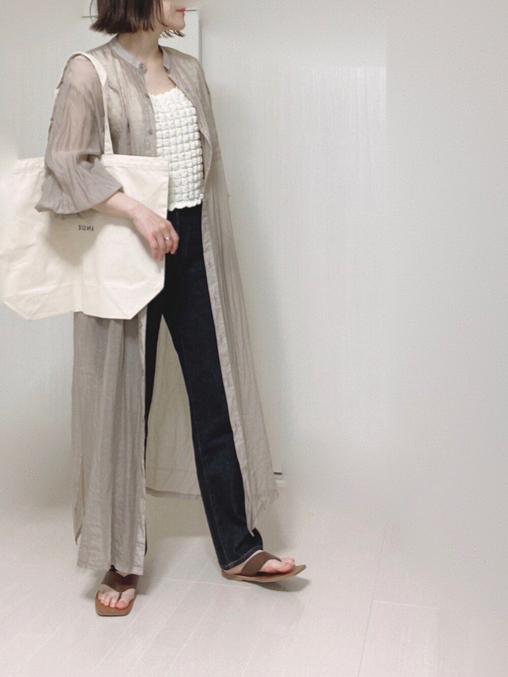 ホワイト系のトートバッグ、ブラウン系のシャツワンピース、ホワイト系のその他トップスを着用したレディースの春コーディネートの3枚目の写真