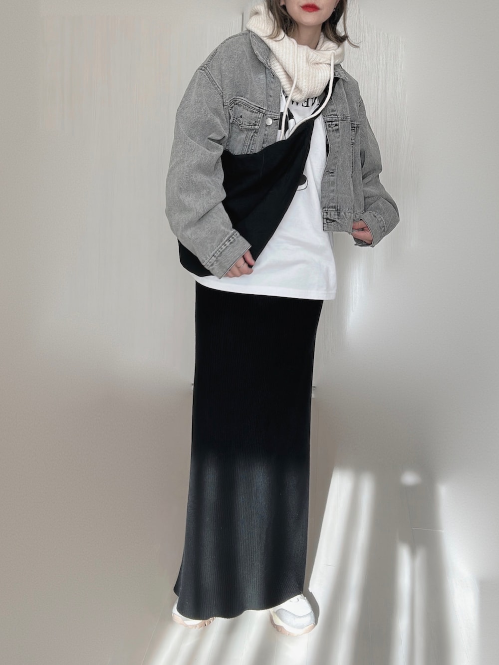 ブラック系のデニムジャケット、ホワイト系のTシャツ/カットソー、ブラック系のスカートを着用したレディースの冬コーディネートの3枚目の写真