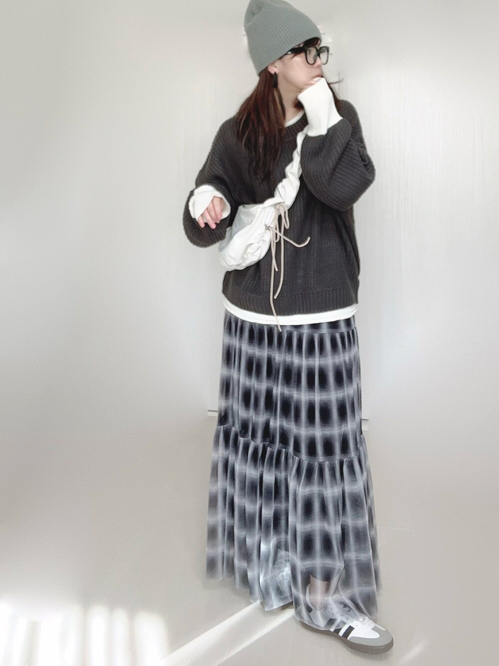 グレー系のニット/セーター、ホワイト系のショルダーバッグ、ブラック系のスカートを着用したレディースの秋コーディネートの2枚目の写真