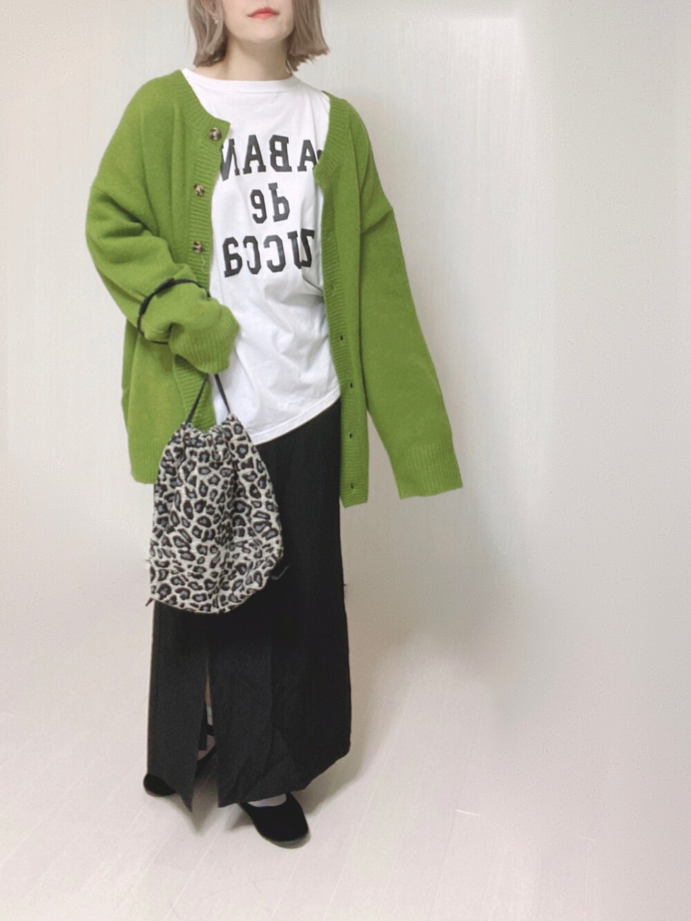 グリーン系のカーディガン/ボレロ、ホワイト系のTシャツ/カットソー、ブラック系のスカートを着用したレディースの秋コーディネートの4枚目の写真