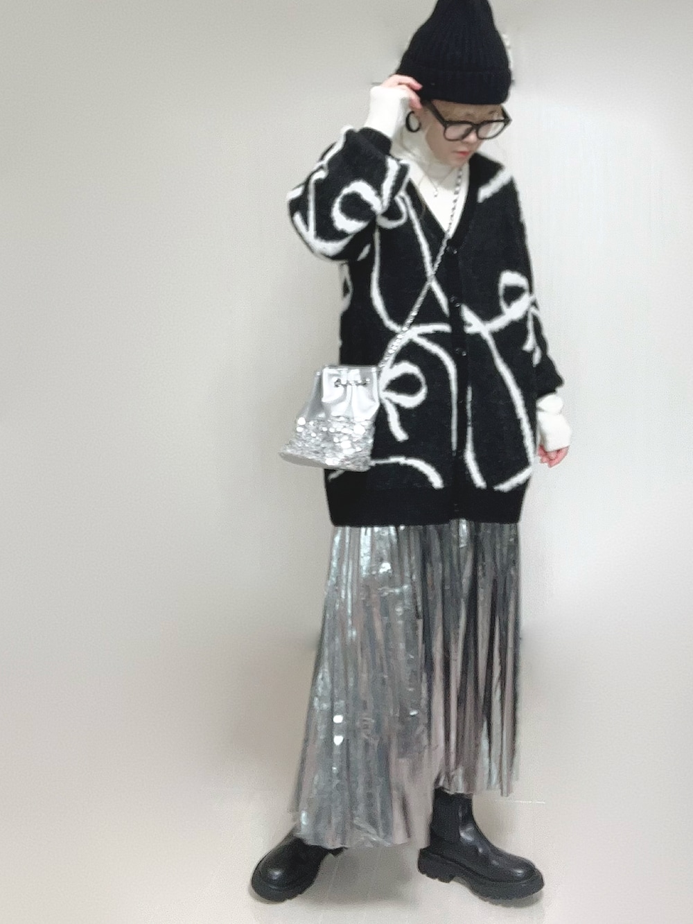 ブラック系のカーディガン/ボレロ、ホワイト系のニット/セーター、ブラック系のブーツを着用したレディースの冬コーディネートの4枚目の写真