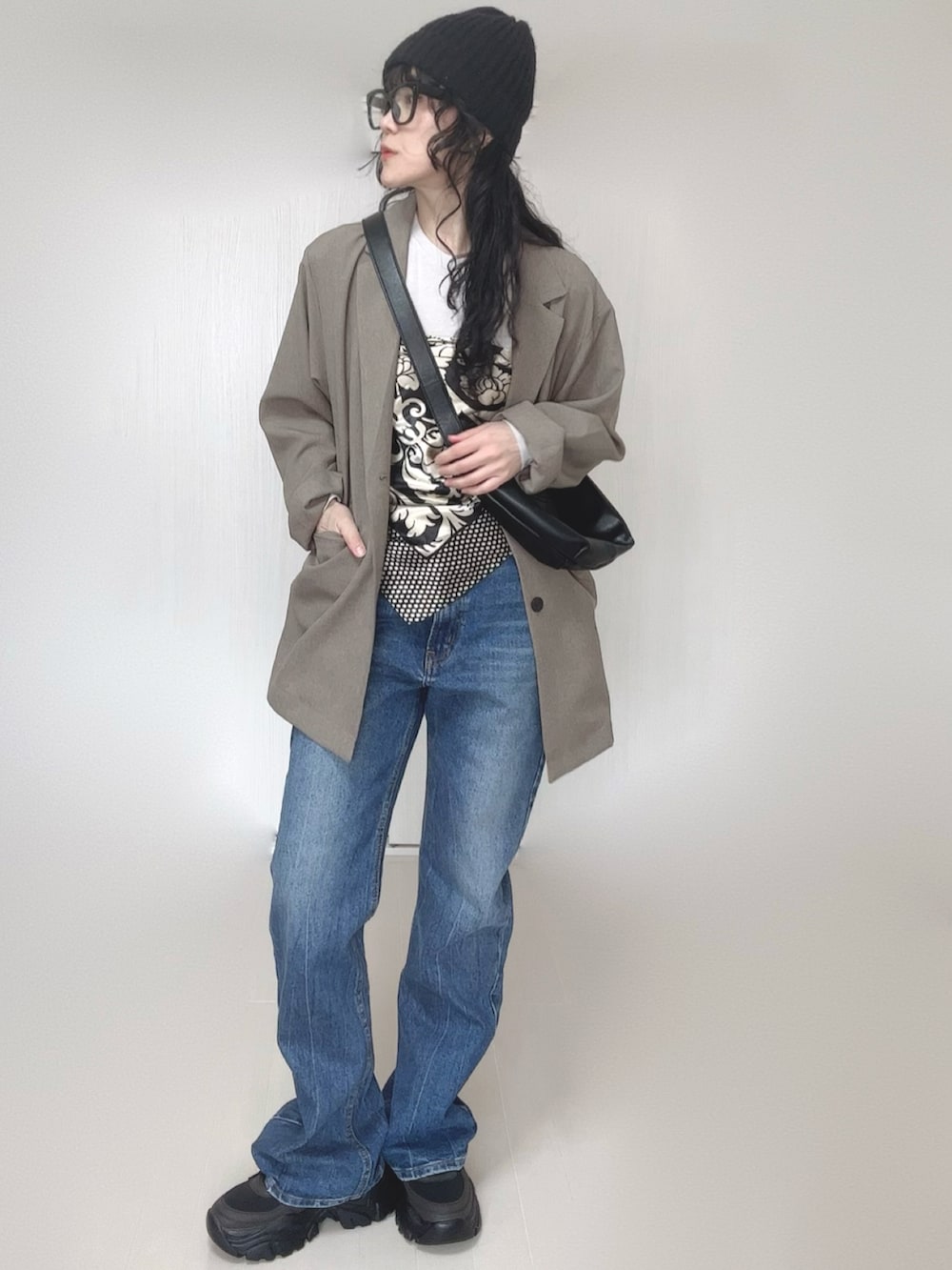 ベージュ系のテーラードジャケット、ブルー系のデニムパンツ、ブラック系のスニーカーを着用したレディースの春コーディネートの4枚目の写真