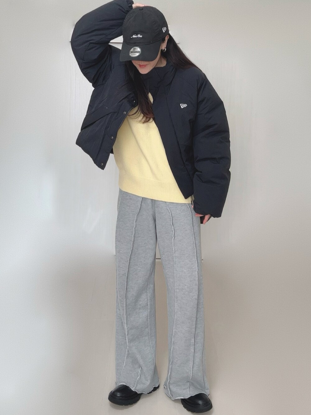 イエロー系のニット/セーター、グレー系のスウェットパンツ、ブラック系のブーツを着用したレディースの冬コーディネートの3枚目の写真