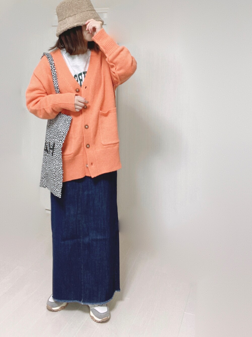 オレンジ系のカーディガン/ボレロ、ブルー系のデニムスカート、ベージュ系のスニーカーを着用したレディースの秋コーディネートの2枚目の写真