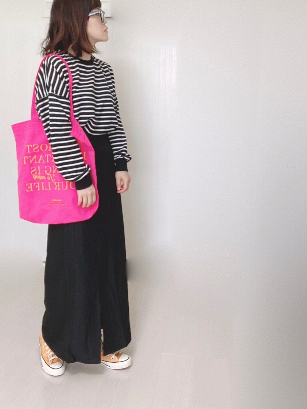 ブラック系のスカート、ホワイト系のTシャツ/カットソー、ピンク系のトートバッグを着用したレディースの秋コーディネートの5枚目の写真