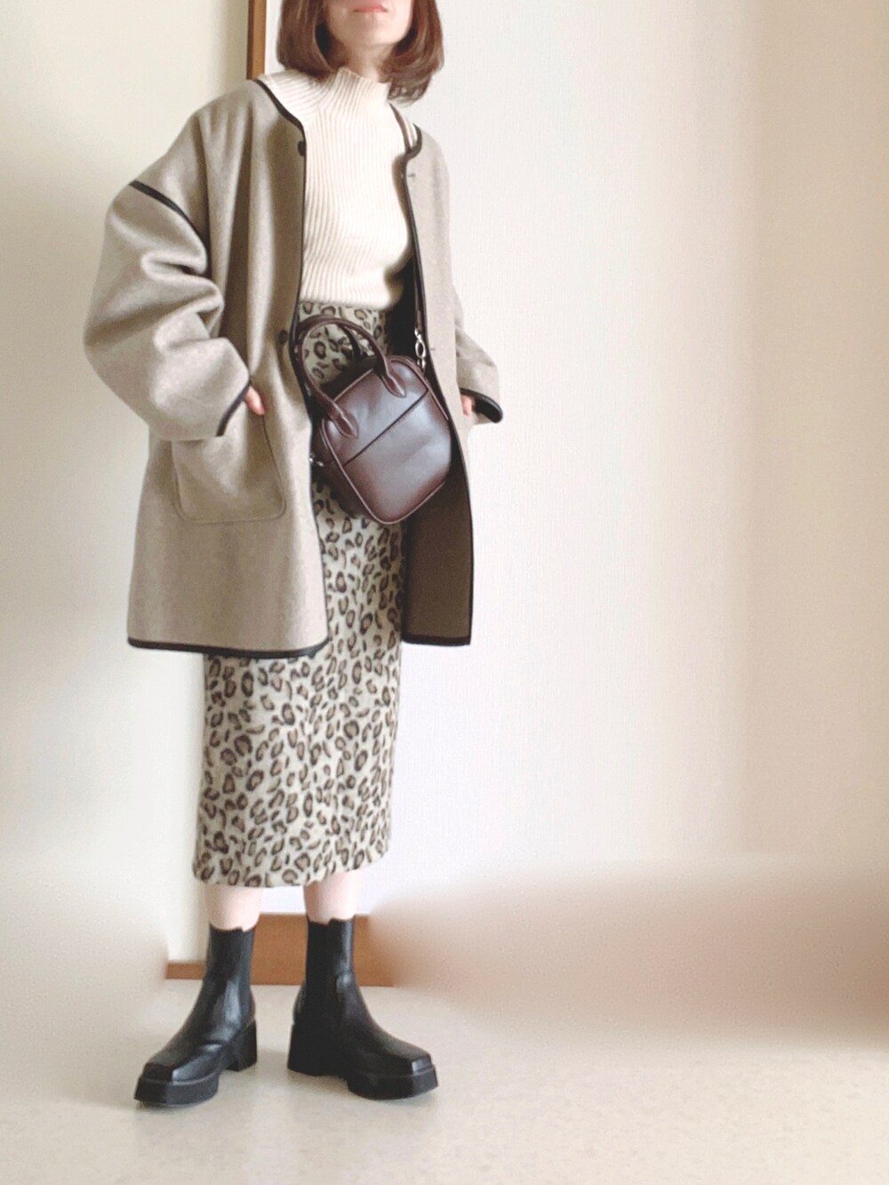 ブラック系のブーツ、ベージュ系のその他アウター、ホワイト系のニット/セーターを着用したレディースの秋コーディネートの2枚目の写真