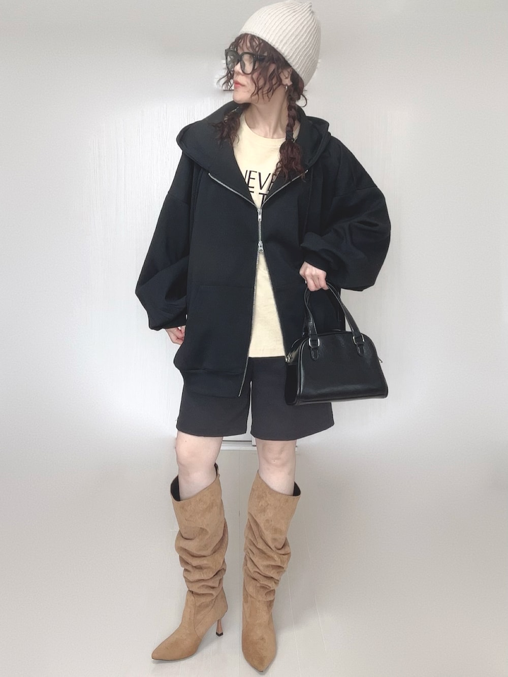 ブラック系のパーカー、ブラック系のボストンバッグ、ベージュ系のTシャツ/カットソーを着用したレディースの冬コーディネートの3枚目の写真