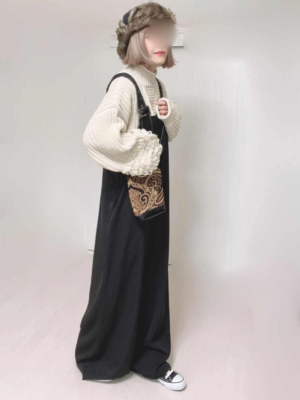 ホワイト系のニット/セーター、ブラック系のサロペット/オーバーオール、ブラック系のショルダーバッグを着用したレディースの秋コーディネートの3枚目の写真