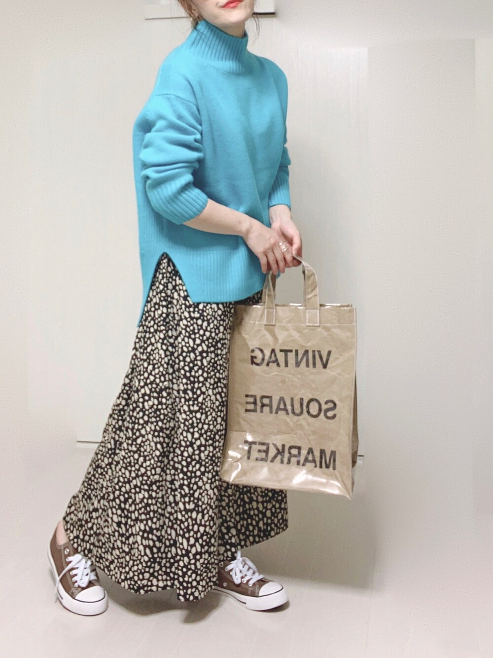 ブルー系のニット/セーター、グリーン系のトートバッグ、ブラック系のスカートを着用したレディースの秋コーディネートの2枚目の写真