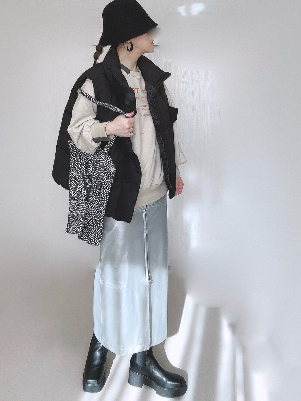 ベージュ系のスウェット、シルバー系のスカート、ブラック系のダウンベストを着用したレディースの冬コーディネートの2枚目の写真