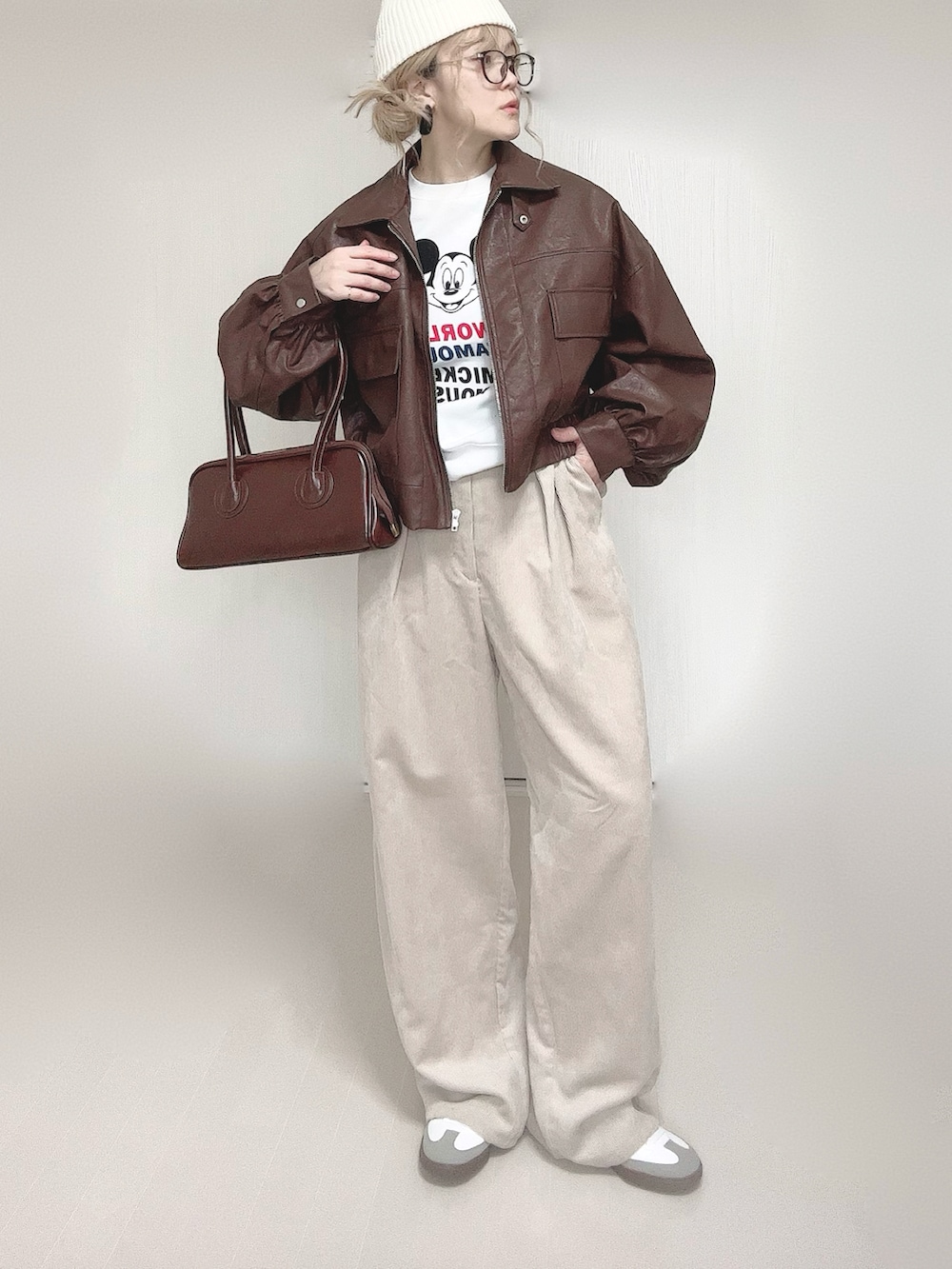 ブラウン系のブルゾン、ブラウン系のショルダーバッグ、ベージュ系のスラックスを着用したレディースの冬コーディネートの2枚目の写真